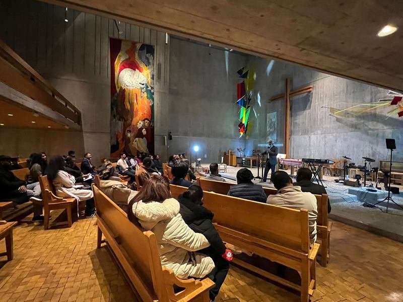 A wide view of the sanctuary during a gathering, with the band and the congregation in the pews