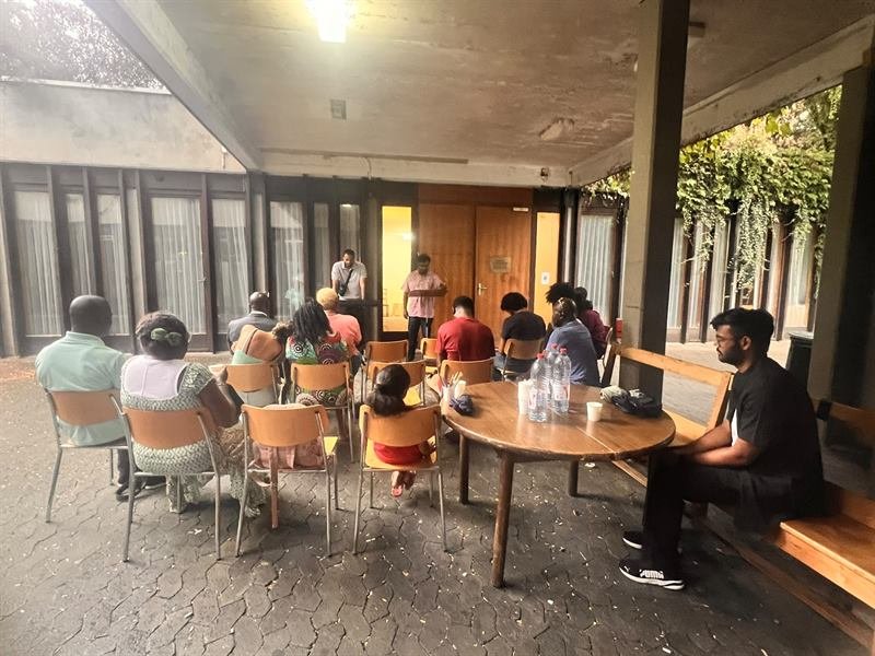 The congregation gathered on chairs in the covered courtyard on a summer evening