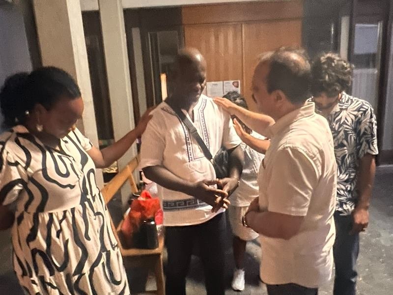 Two believers praying over a man with hands on his shoulders