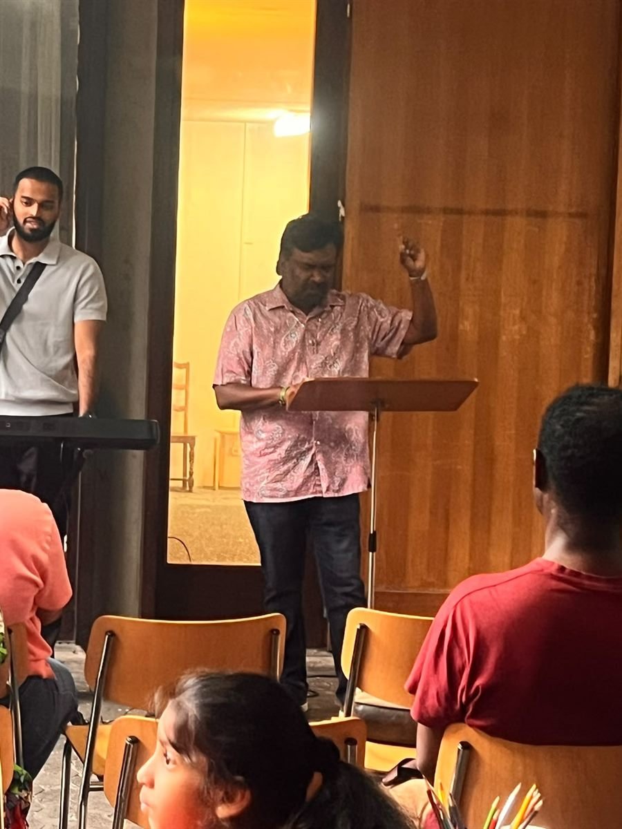 Evangelist Norman J. Sinappen preaching at the lectern during a weekday gathering