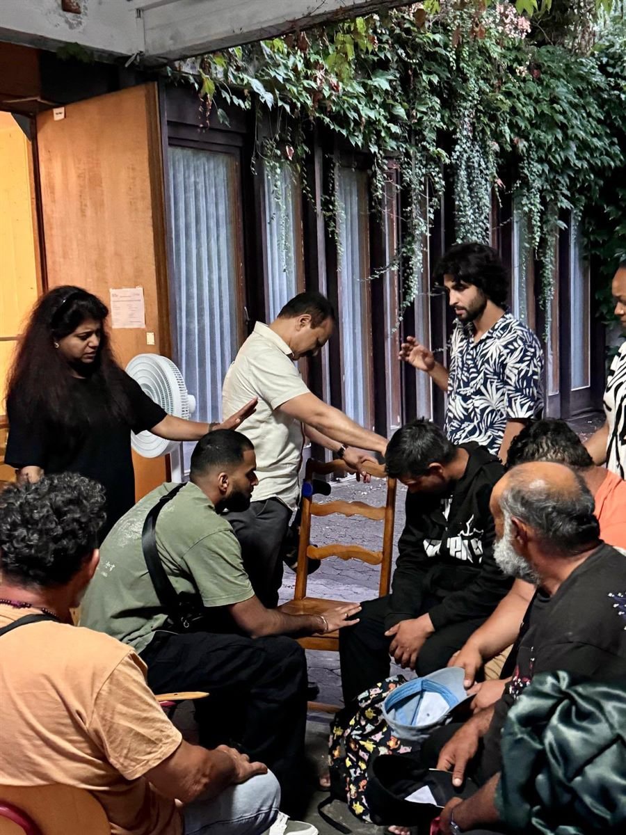 Members of the prayer team laying hands on a young man during a gathering