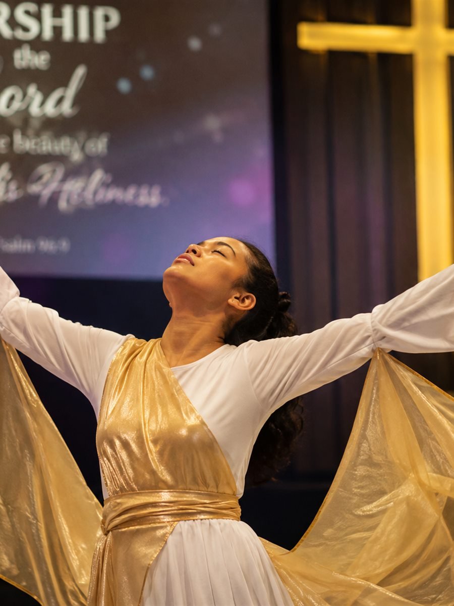 A tambourine dancer worshipping with arms outstretched before the cross